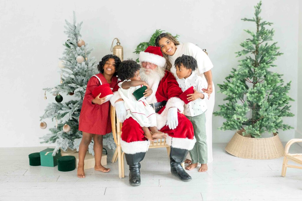 Utah Santa photos of a family laughing with Santa in a bright Christmas studio by Kamee Valdez Photo.