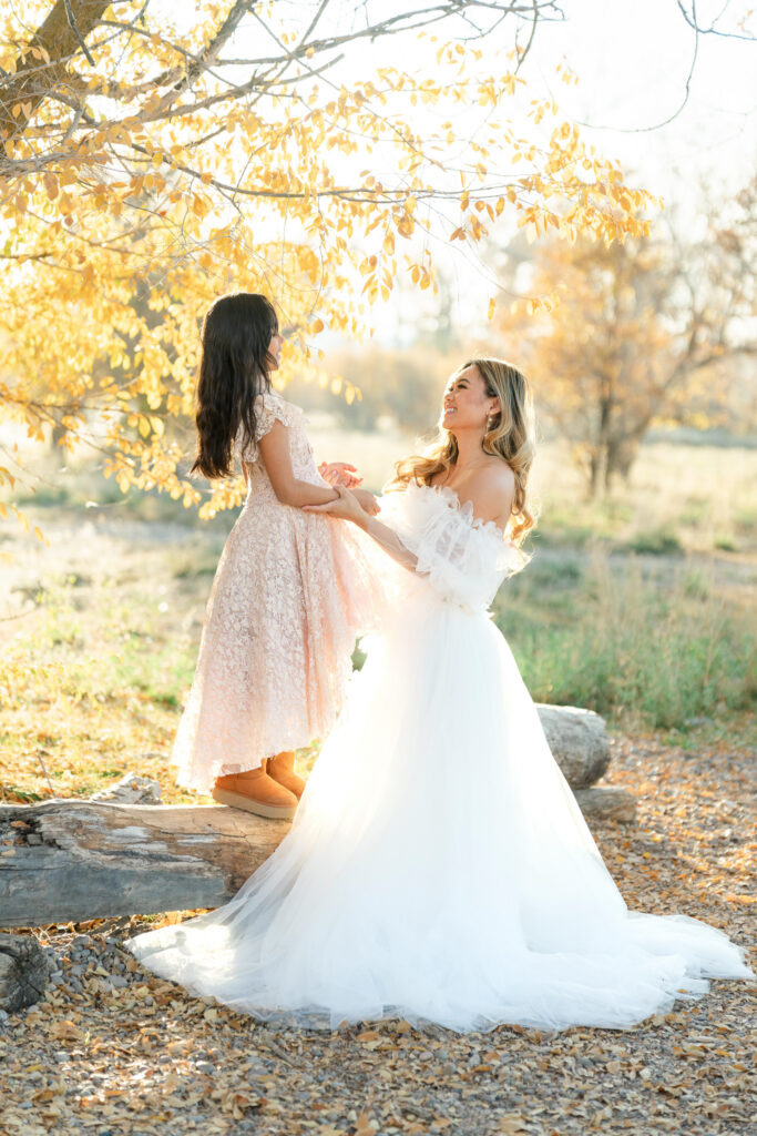 Mother and daughter laughing together beneath colorful autumn leaves during a Utah fall family outing, photographed by Kamee Valdez Photo