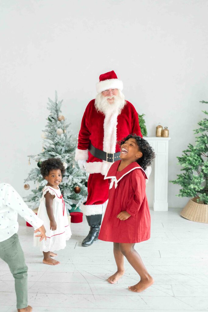 Candid Utah Santa photos of children laughing and playing with Santa in a light-filled Christmas studio.