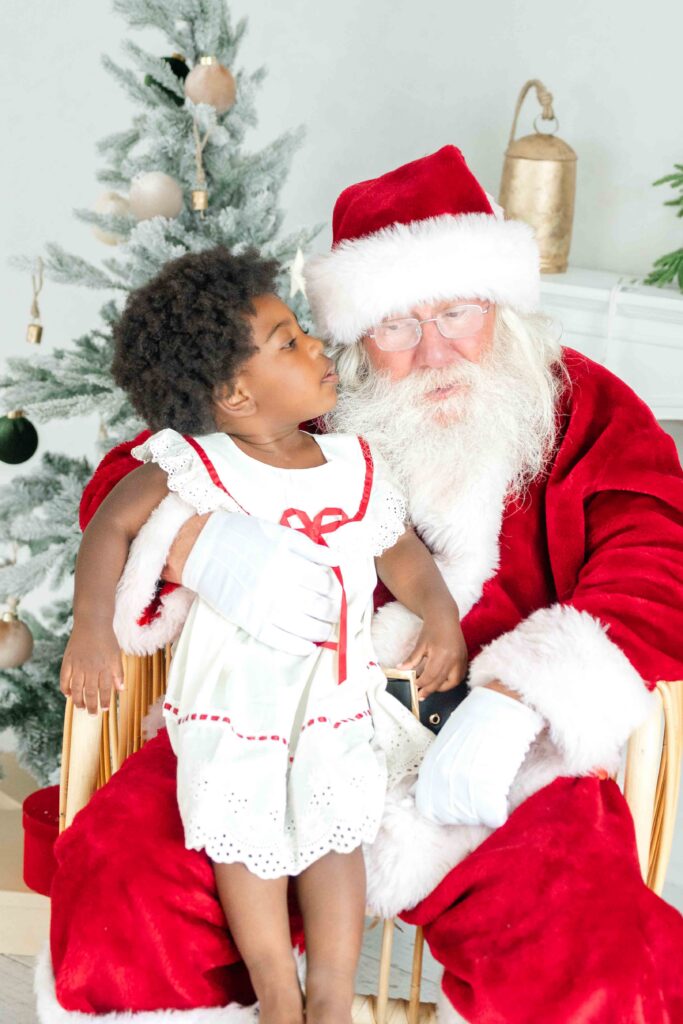 Little girl smiling with Santa during Utah Santa photos photographed by Kamee Valdez Photo.