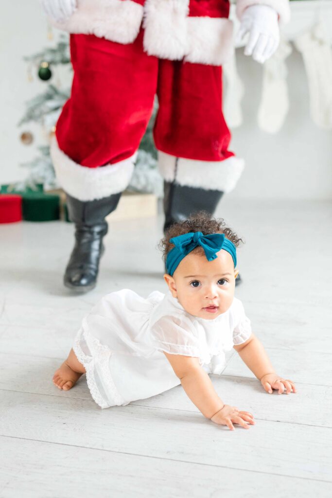 Baby crawling through a bright Christmas studio during Utah Santa photos by Kamee Valdez Photo.