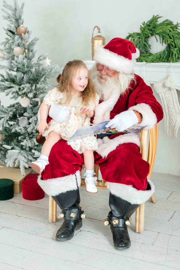 Utah Santa photos of a little girl sitting with Santa and reading a Christmas book by Kamee Valdez Photo.